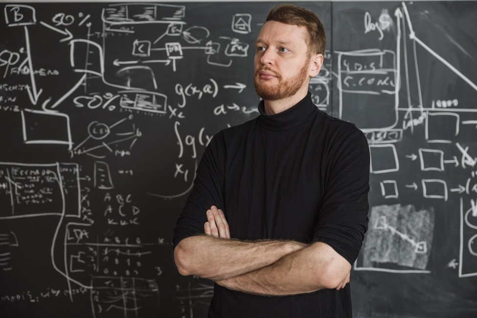 foto van Andres Karjus, man die voor een krijtbord met daarop wetenschappelijke formules staat