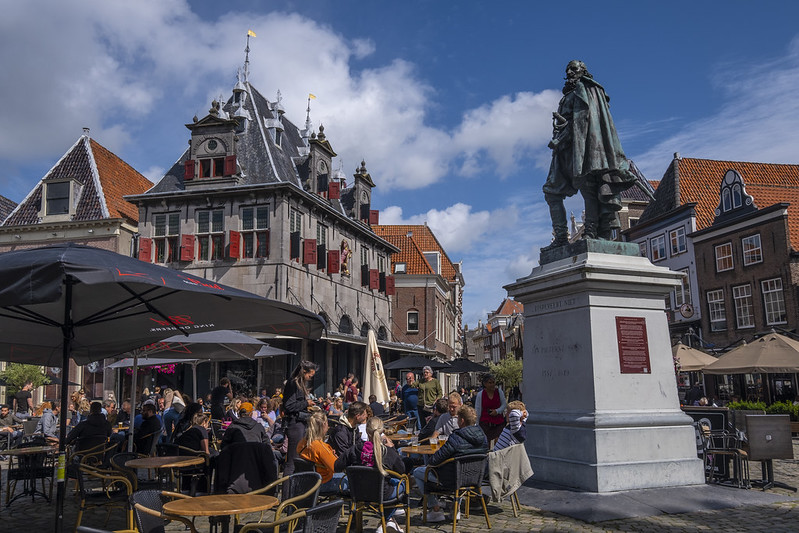 Foto van een zonnige dag in Hoorn met het standbeeld van J.P. Coen naast een vol terras.