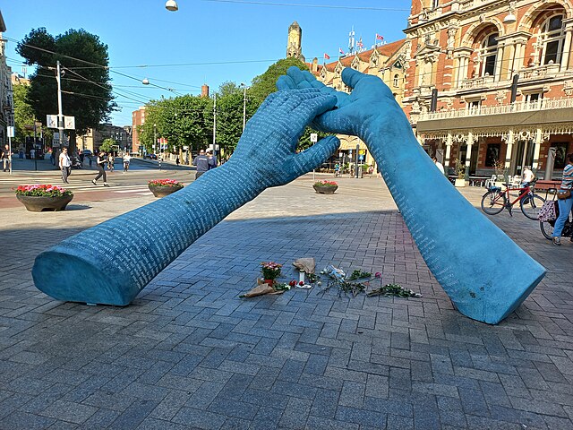 Foto van het monument voor Peter R. de Vries. Een beeld van twee onderarmen waarbij de handen elkaar aanraken in de vorm van een driehoek.