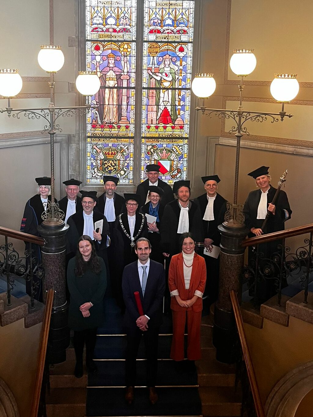 Foto van de gepromoveerde Cedric waterschoot met zijn promotoren, paranimfen, en de commissieleden op de trappen van het Academiegebouw in Utrecht.