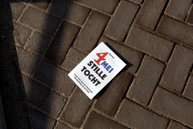 Flyer met tekst: 4 mei stille tocht. Loop mee naar de Nationale Dodenherdenking op de Dam. Daar delen ooggetuigen hun verhalen over de oorlog.
