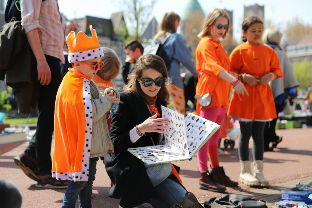 Kinderen in het oranje verkleed op de vrijmarkt met Koningsdag.