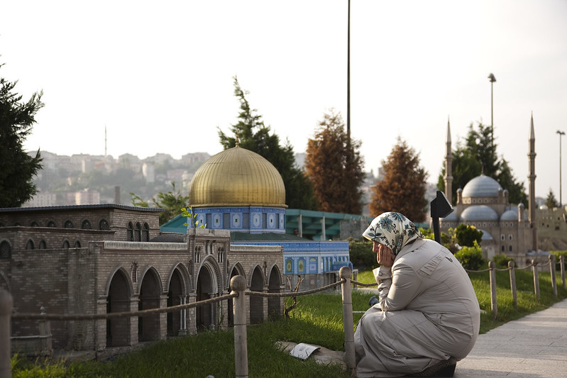 Foto van Miniatürk in Istanbul. Iemand zit voor een miniatuurversie van een moskee.